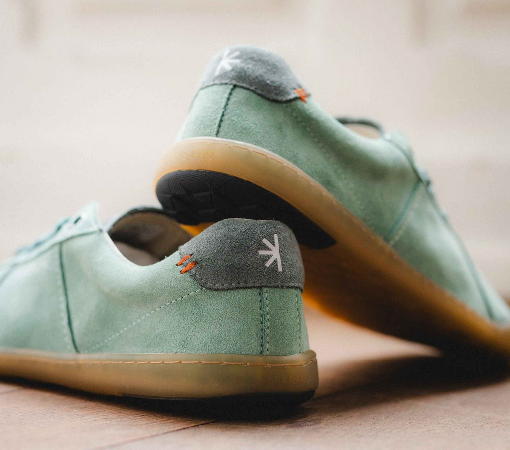 Blusun Sneaker green jade sage grün komplett aus Velour Leder, mit etwas dunkler grünen Schnürsenkeln, laces, and der Ferse und an der Zunge grauer Kontrast. Die Sohle ist Honig farbig und sehr dünn für's Barfußgefühl. Foto von hinten, ein Paar steht schräg übereinander.