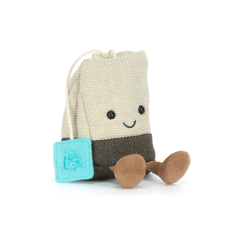 Lächelnder Kuscheltier Teebeutel von Jellycat aus beige, grauem Canvas mit hellbraunen Cord-Beinchen und einem türkisen Jellycat Tag, schräge Vorderansicht