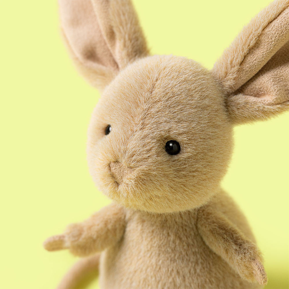 Nahaufnahme der flauschigen Springmaus vor hellgrünem Hintergrund mit strahlend schwarzen Augen, Jellycat Jerboa Imagebild